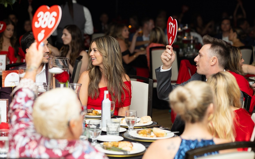 Table of guests holding up bid paddles